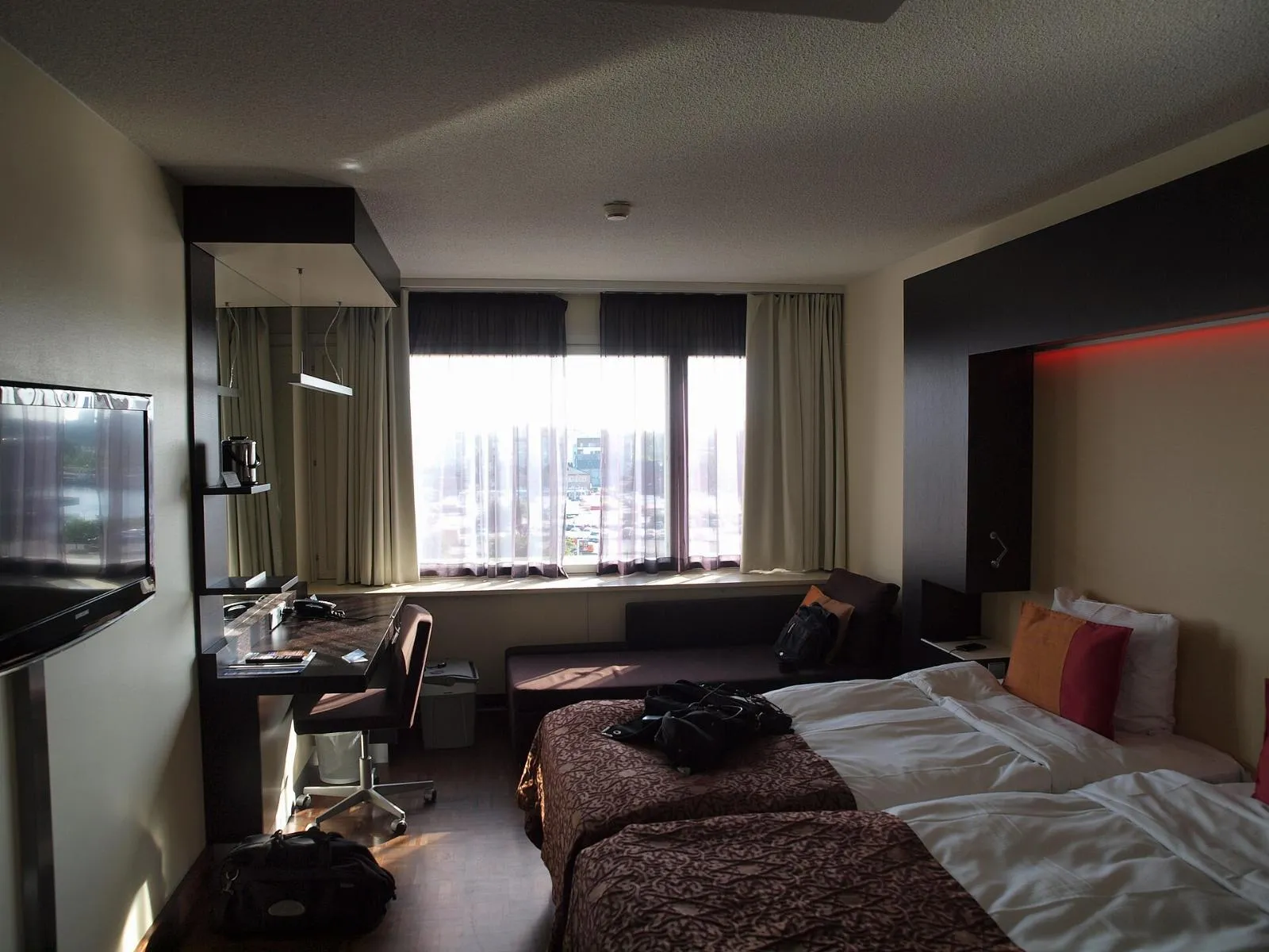 A hotel room with a desk by the window